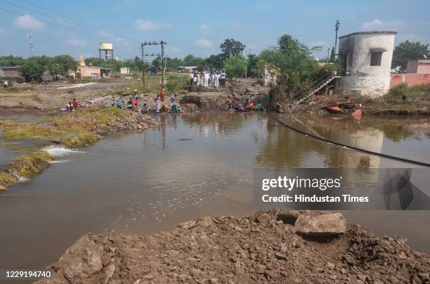 Villagers of Swami Chincholi village stand at other side of the road that washed away due to force of flood, on October 19, 2020 in Pune, India. The...