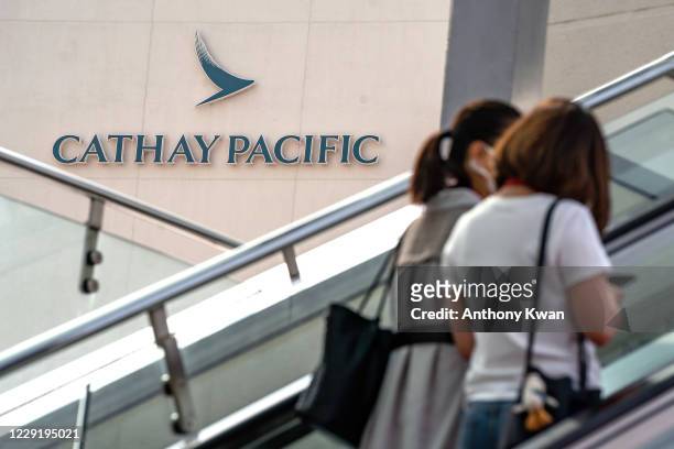 People walk in front of a signage outside Cathay Pacific City building, the headquarters of Cathay Pacific Airways, on October 21, 2020 in Hong Kong,...