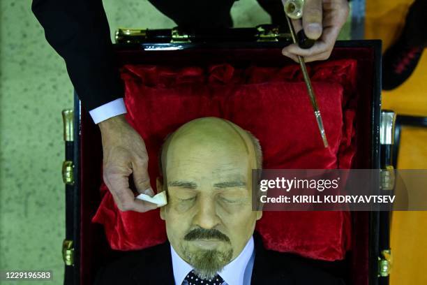 Participant applies makeup on the copy of Soviet state founder Vladimir Lenin's body during a funeral exhibition in Moscow on October 21, 2020. The...