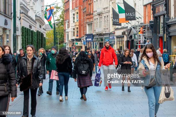 Shoppers walk through a busy Grafton Street in Dublin on October 21, 2020 as Ireland prepares to enter a second national lockdown to stem the spread...