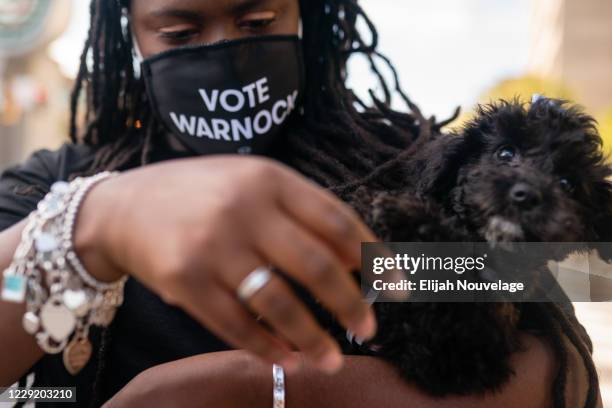 Tiffanie Morris, supporter of Democratic U.S. Senatorial candidate Raphael Warnock holds her 11-week-old Maltepoo Fannie Lou, named after voting and...