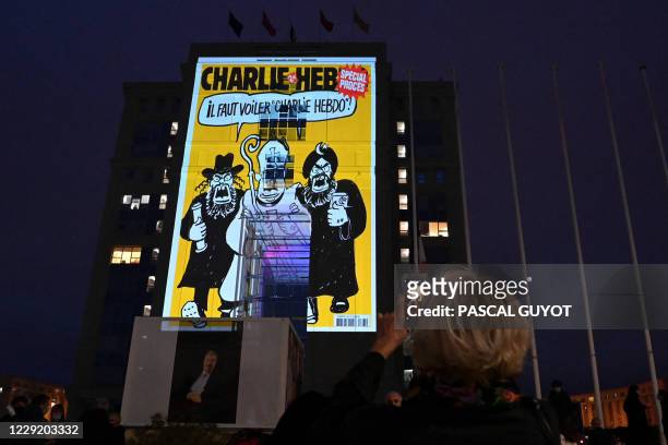 Woman takes a picture of cartoons of French satirical weekly newspaper Charlie Hebdo projected onto the facade of the Hotel de Region in Montpellier,...