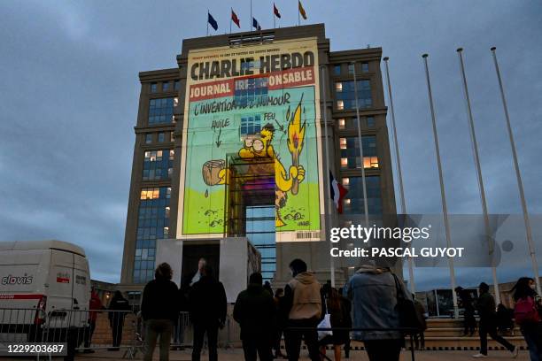 People look at cartoons of French satirical weekly newspaper Charlie Hebdo projected onto the facade of the Hotel de Region in Montpellier, on...