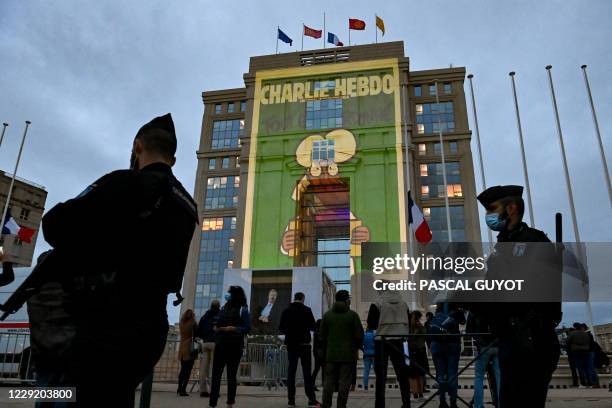 People look at cartoons of French satirical weekly newspaper Charlie Hebdo projected onto the facade of the Hotel de Region in Montpellier, on...