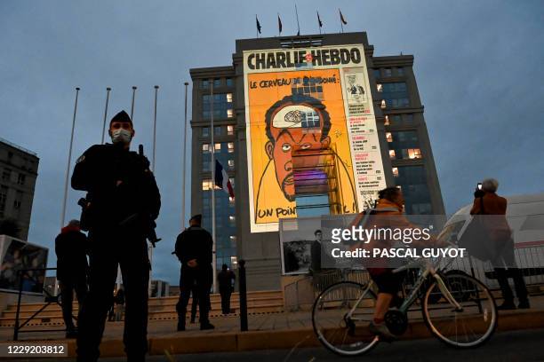 Police officers stand guard as cartoons of French satirical weekly newspaper Charlie Hebdo are projected onto the facade of the Hotel de Region in...
