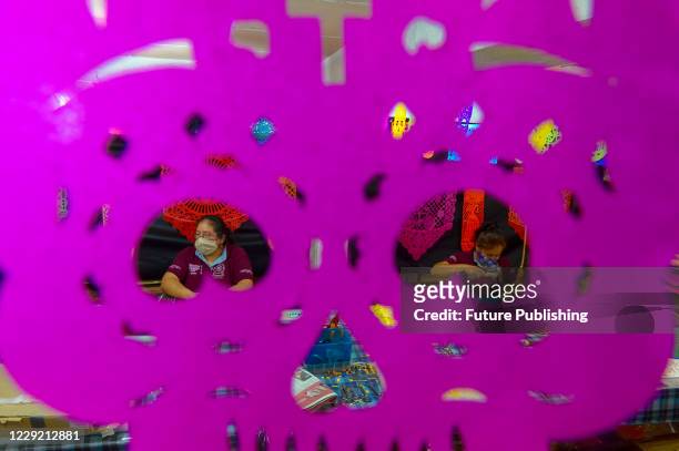 Worker from the "Taller de Yuriria" wears a protective mask, while using a template to cutting a traditional Mexican paper 'Papel Picado', that is...