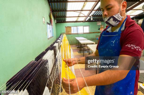 Worker from the "Taller de Yuriria" wears a protective mask, while holds a Mexican cut paper 'Papel Picado', that is used to decorate offerings and...