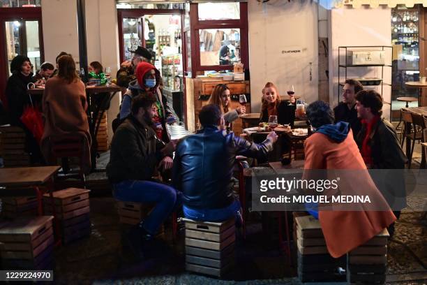 People enjoy drinks and food at a terrace in the Navigli district in southern Milan on October 22 before the closing of the sites. - Lombardy region...