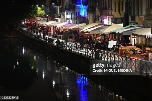 People stroll along a canal in the Navigli district in southern Milan on October 22 before the closing of bars and restaurants. - Lombardy region...