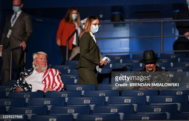Debate worker walks towards US professional golfer John Daly and musician Kid Rock providing them with a facemask to wear ahead of the final...