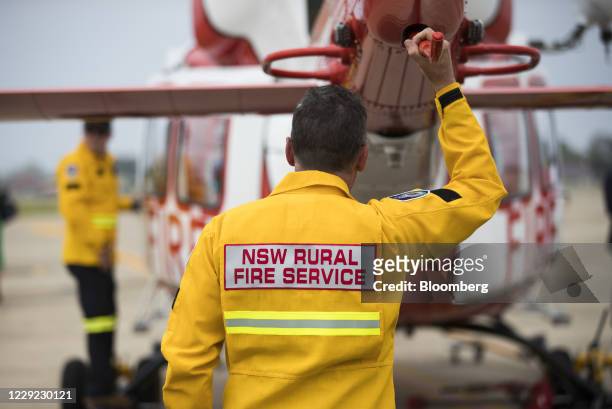 Member of the NSW Rural Fire Service stands near a helicopter during a display by the NSW Rural Fire Service, Fire and Rescue NSW and NSW State...