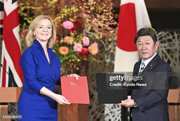 Japanese Foreign Minister Toshimitsu Motegi and British International Trade Secretary Liz Truss pose in Tokyo on Oct. 23 after signing a post-Brexit...