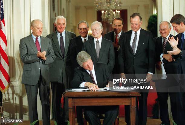 President Bill Clinton signs side agreements to the North American Free Trade Agreement surrounded by three former US Presidents and congressional...