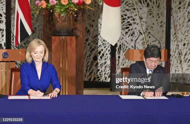 Japanese Foreign Minister Toshimitsu Motegi and British International Trade Secretary Liz Truss sign a post-Brexit bilateral free trade agreement in...