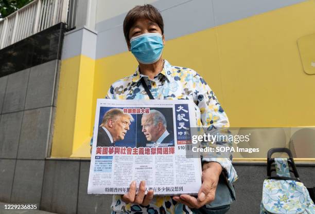 Woman wears a facemask distributes the multi-language newspaper The Epoch Times newspaper featuring the US election debate between Donald J. Trump...