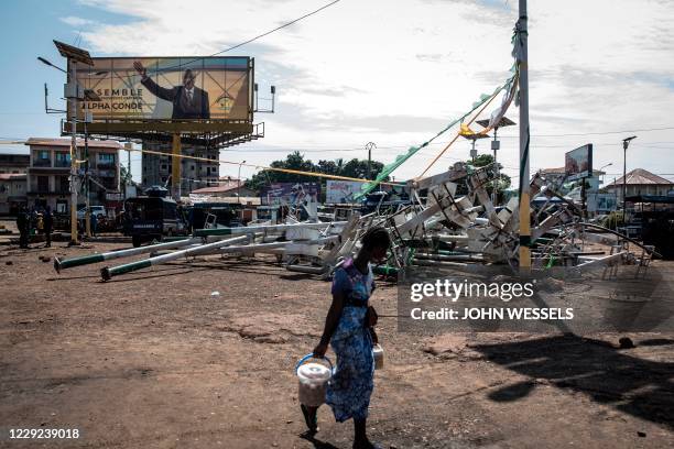 Woman walks in-front of light poles, broken by protests the day after preliminary presidential election results were released in Conakry on October...