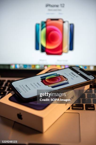 In this photo illustration an iPhone 12 smartphone and its box is placed on keyboard of a MacBook Pro laptop. IPhone 12 series was released on Oct...