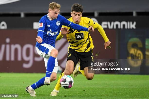 Dortmund's US midfielder Giovanni Reyna and Schalke's German defender Kilian Ludewig vie for the ball during the German first division Bundesliga...