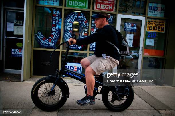 Man rides his electric bike by Biden campaign posters on October 23, 2020 in Scranton, Pennsylvania. - In Scranton, Joe Biden's hometown,...