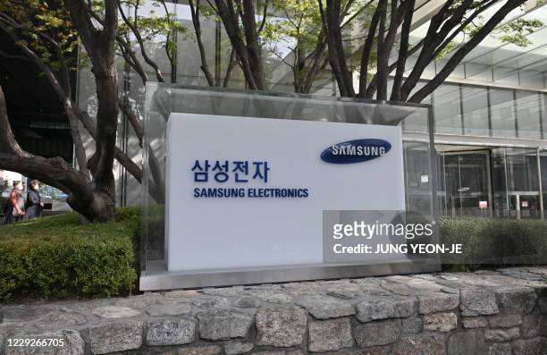 People walk past the logo of Samsung Electronics at the company's Seocho building in Seoul on October 25, 2020 - Samsung Electronics chairman Lee...