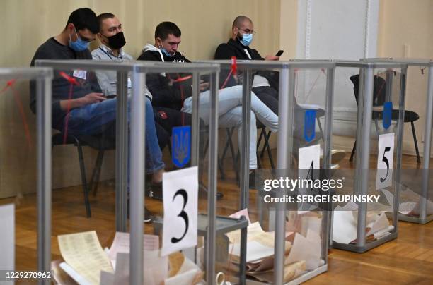 Observers sit near ballot boxes in a polling station in Kiev during local election in Ukraine on October 25, 2020. - Ukrainians were voting on on...