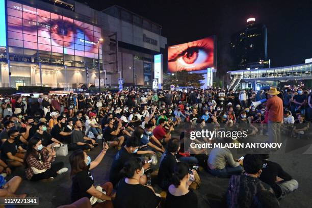 Pro-democracy protesters take part in an anti-government rally, as giant eyes appear on large advertising screens behind them, in Bangkok on October...