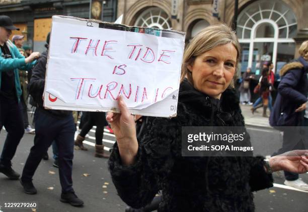 Woman hold placard proclaiming the Tide is Turning during the march. Unite for Freedom movement - the Anti lockdown, anti vaccine, anti government...