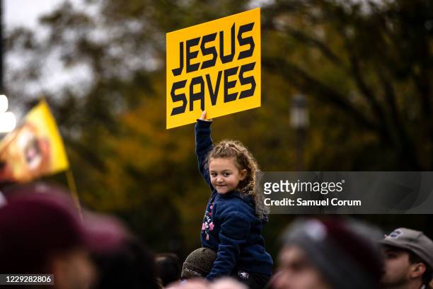 Girl holds up a sign reading "Jesus Saves" at a concert by evangelical musician Sean Feucht on the National Mall on October 25, 2020 in Washington,...