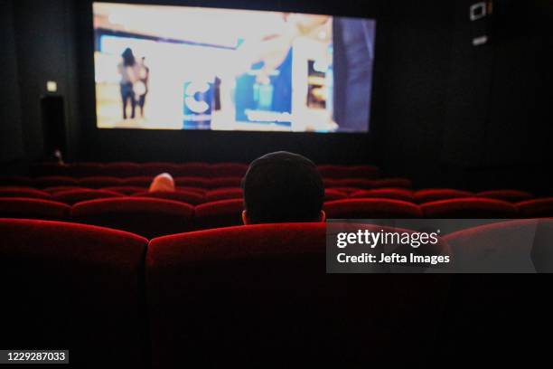 People sit near seats marked for physical distancing at Cinepolis movie theatre following the ease of coronavirus restrictions in Jakarta, Indonesia,...