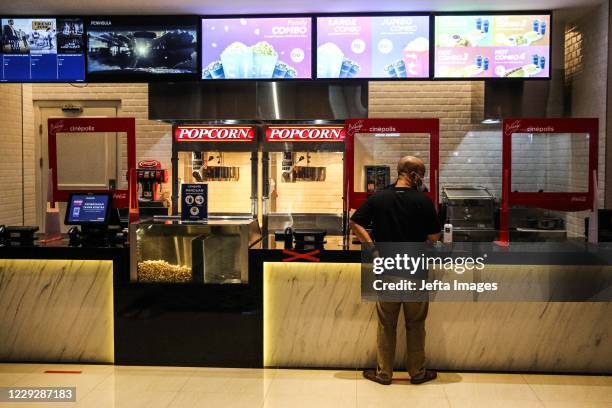 An visitor by some food at food counter before he enters the Cinepolis movie theatre following the ease of coronavirus restrictions in Jakarta,...