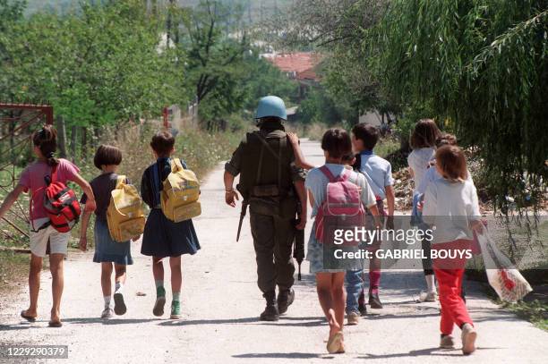 United Nations Protection Force French soldier escorts on August 14, 1993 a group of children after they left their Kobilja Gava school in Sarajevo...