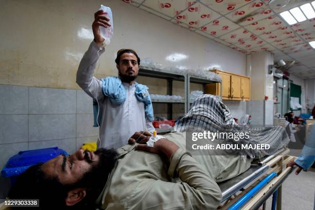 Man holds an intravenous bag for a victim injured in a bomb explosion at a religious school, at a hospital in Peshawar on October 27, 2020. - At...