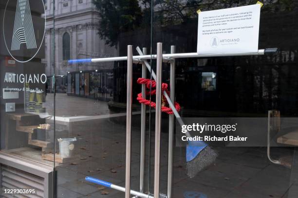 As financial district workers are still working from home, a rope cordon and a broom is wrapped around door handles of a closed wine bar during the...