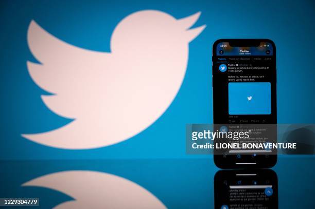 This photograph taken on October 26, 2020 shows the logo of US social network Twitter displayed on the screen of a smartphone and a tablet in...