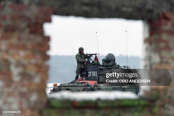 Soldier of the NATO peace implementation cleans on January 02, 1996 his M-16 assault rifle on top of a tank at a US base "Bandit camp" outside the...