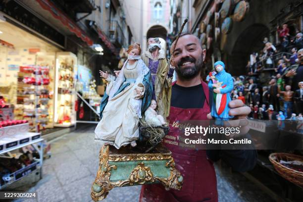 The artisan Genny Di Virgilio, shows his creation, the nativity with face masks and a doctor, in front of his shop in the street of the Neapolitan...