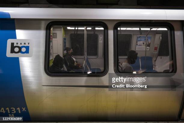 People wearing protective masks sit onboard a train at a Bay Area Rapid Transit train station in San Francisco, California, U.S., on Monday, Oct. 26,...