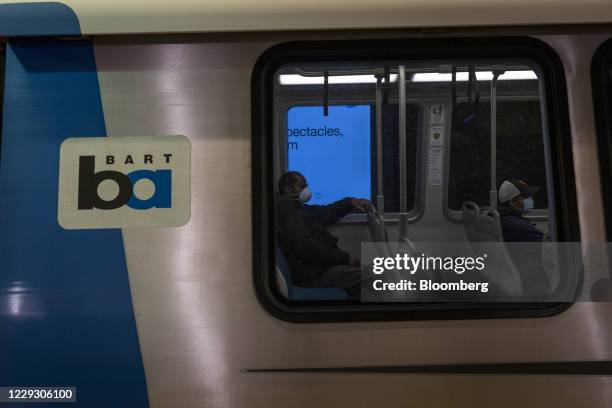 People wearing protective masks sit onboard a train at a Bay Area Rapid Transit train station in San Francisco, California, U.S., on Monday, Oct. 26,...