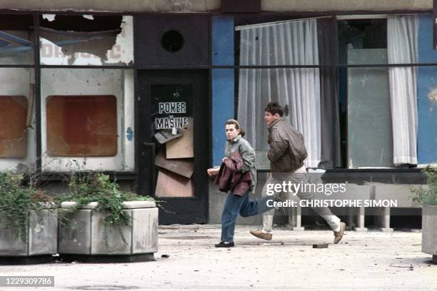 Local residents run in a street in Sarajevo on June 19, 1992. A two-day-old cease fire in this besieged city collapsed June 17 as heavy artillery,...
