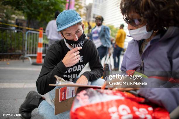 Volunteer helps a woman complete an early ballot form outside of Philadelphia City Hall at the satellite polling station on October 27, 2020 in...