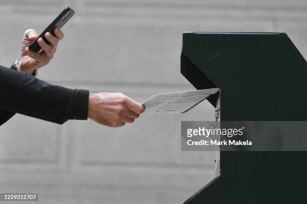 Man photographs himself depositing his ballot in an official ballot drop box while a long line of voters queue outside of Philadelphia City Hall at...