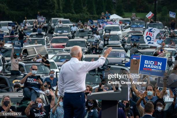 Democratic presidential nominee Joe Biden waves to supporters as he finishes speaking during a drive-in campaign rally in the parking lot of...