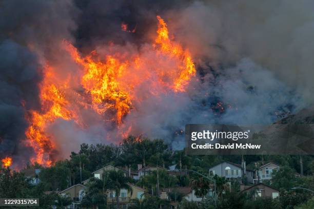 Flames rise near homes during the Blue Ridge Fire on October 27, 2020 in Chino Hills, California. Strong Santa Ana Winds gusting to more than 90...