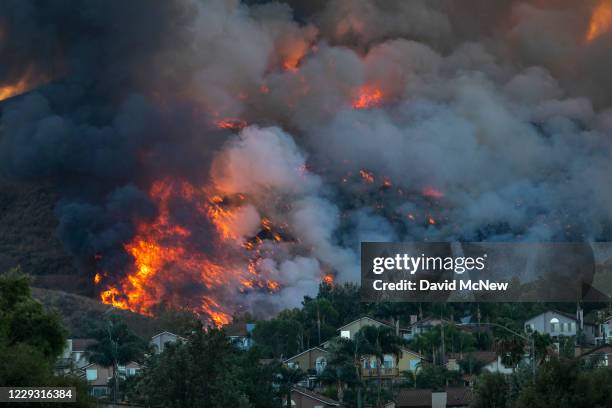 Flames rise near homes during the Blue Ridge Fire on October 27, 2020 in Chino Hills, California. Strong Santa Ana Winds gusting to more than 90...