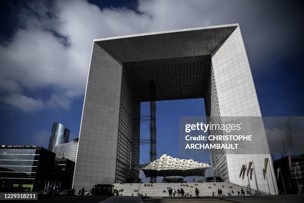 People walk by the Grande Arche at the business district of La Defense west of Paris on October 16 as the country faces a new wave of infections to...