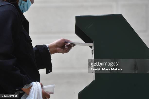 Woman deposits her ballot in an official ballot drop box at the satellite polling station outside Philadelphia City Hall on October 27, 2020 in...
