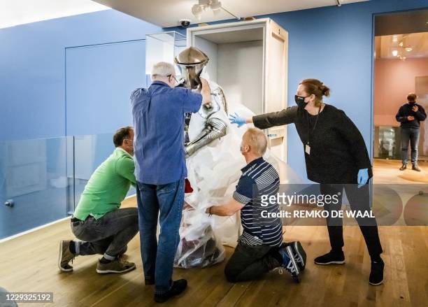 Employees adjust a suit of German tournament armour from around 1500, for the exhibition "Romanovs under the spell of the knights" at The Hermitage...