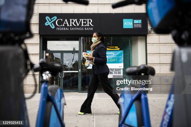 Pedestrian wearing a protective mask walks past a Carver Federal Savings Bank branch in the Harlem neighborhood of New York, U.S., on Tuesday, Oct....