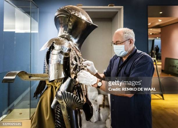 An employee adjusts a suit of German tournament armour from around 1500, for the exhibition "Romanovs under the spell of the knights" at The...
