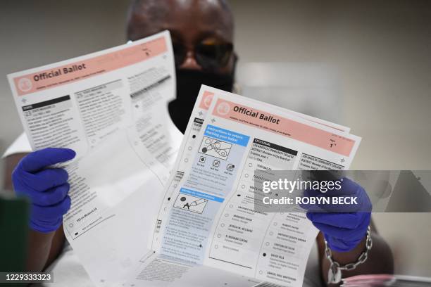 Election workers extract mail-in ballots from their envelopes and examine the ballot for irregularities at the Los Angeles County Registrar...